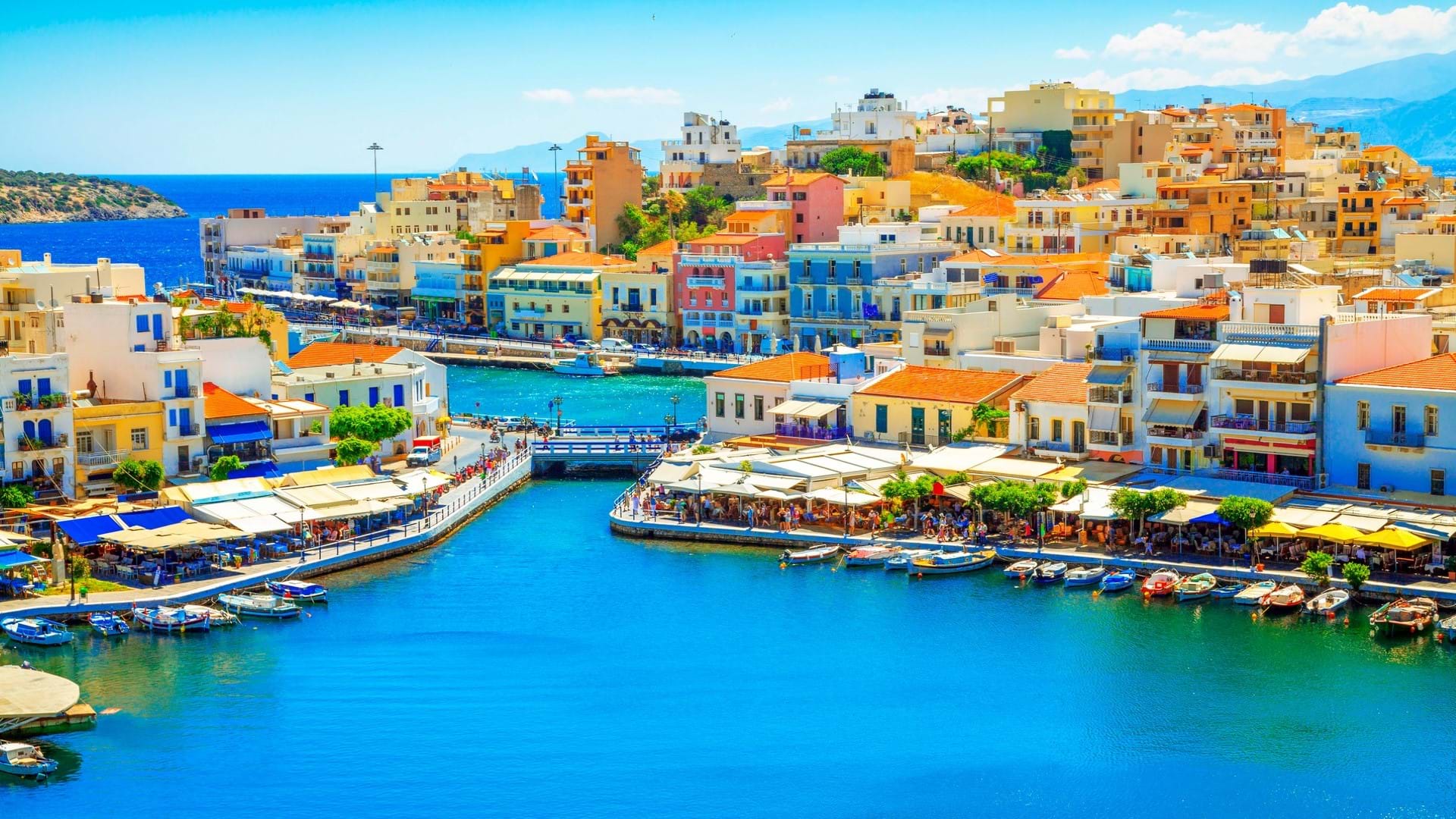 Agios Nikolais mesto na Kritu. Prelep prizor šarenih fasada na kućama, obala, kanal i restorani na obali. Plavetnilo mora.