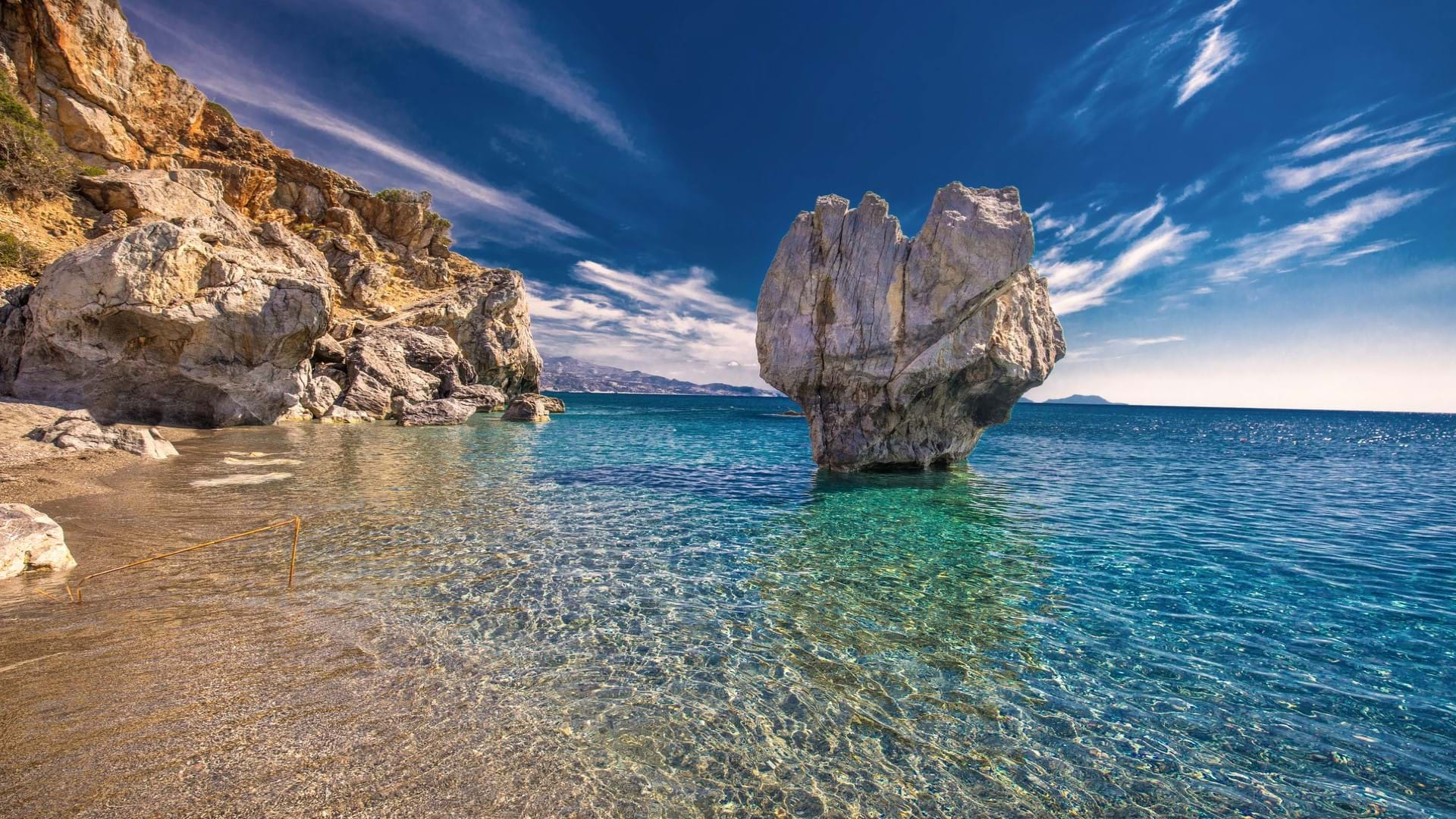 Prelepa plaža na Kritu. Stena koja izlazi iz kristalno čiste vode i sitan pesak koji se sudara sa stenama na obali.