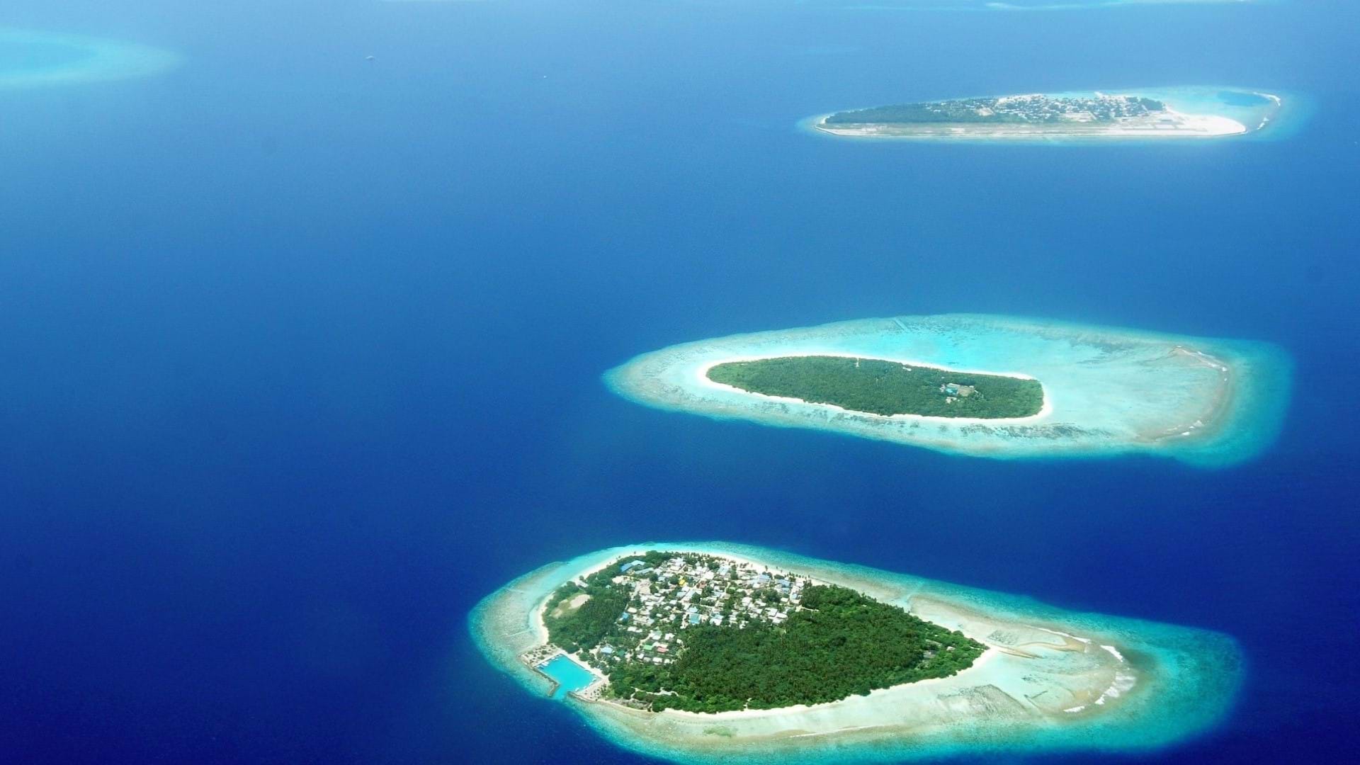 Slika Maldiva slikana iz aviona, ostrva sa tirkiznom bojom mora koja se utapaju u plavetnilo Indijskog okeana