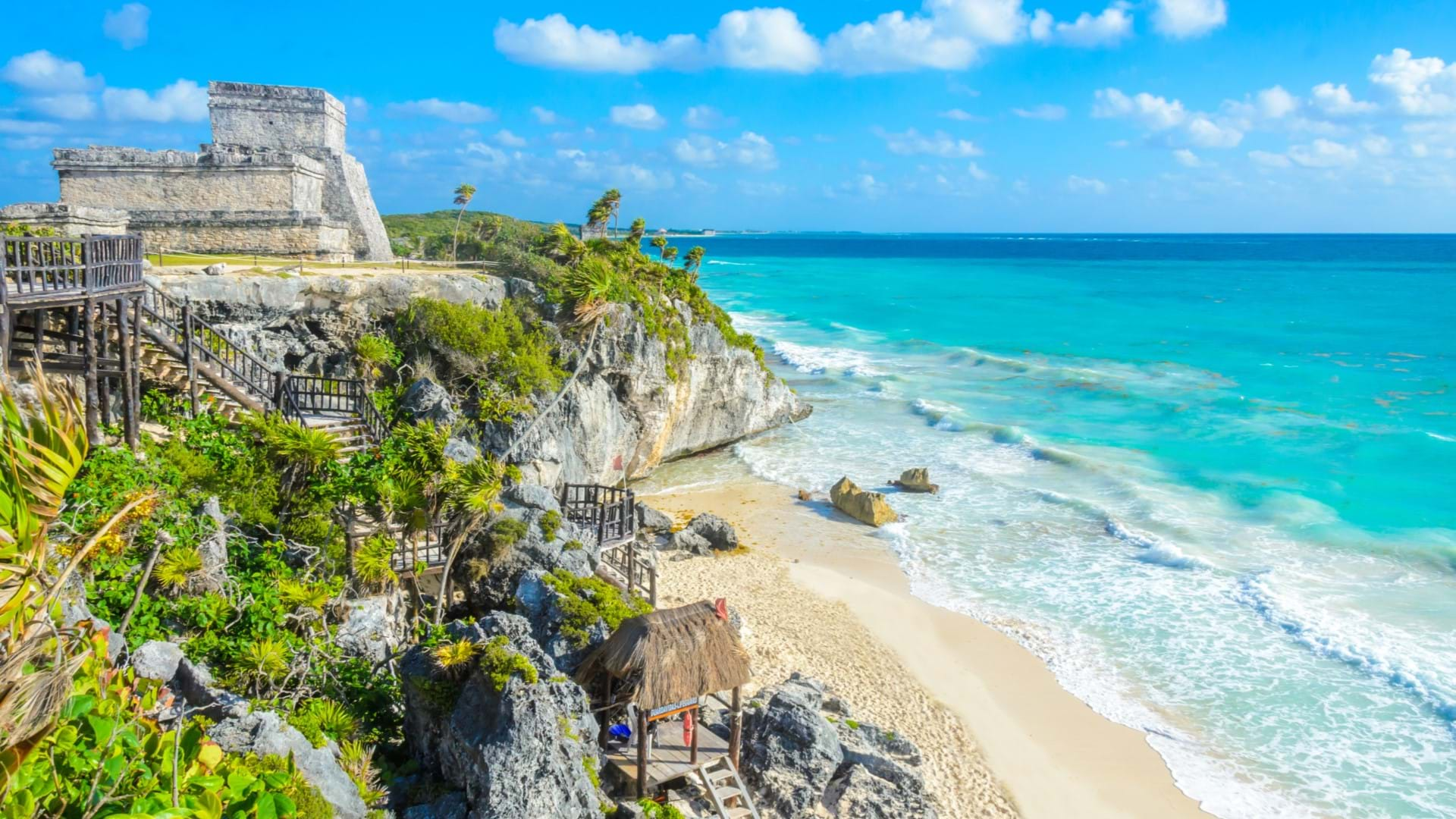 Plaža ispod drevnog grada Tulum u Meksiku na rivijeri Maja. Predivan pogled na građevine maja, tirkizno more i beli pesak koji se sudaraju sa stenama.